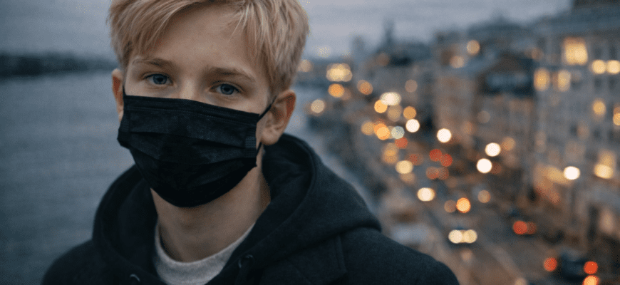 Мальчик в маске смотрит на камеру